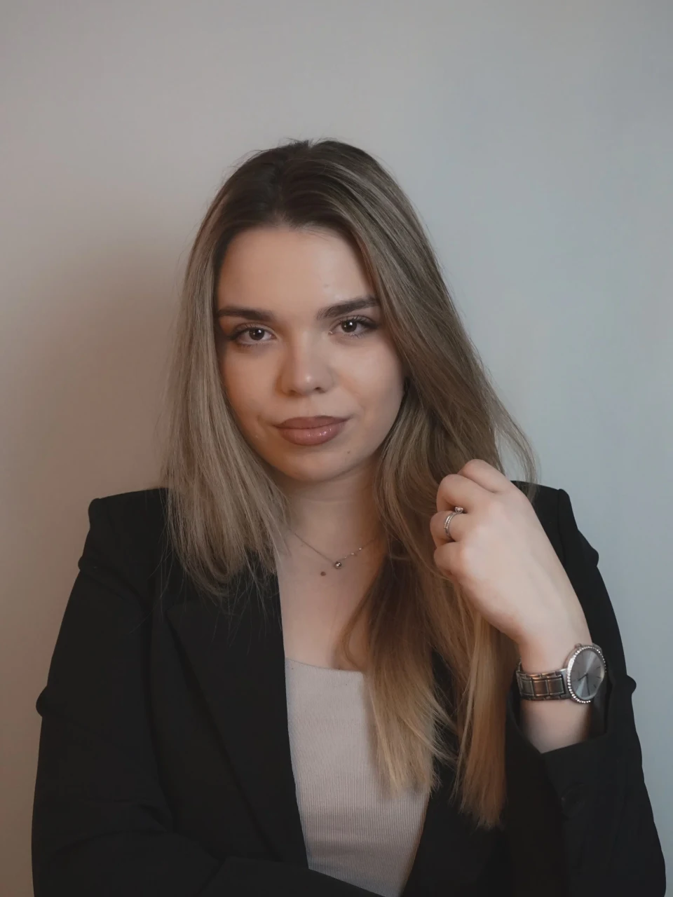 Portret žene u crnom sakou ispred neutralnog zida