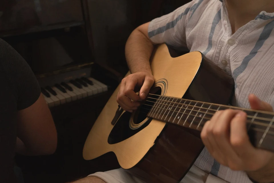 Detalj ruku koje sviraju akustičnu gitaru